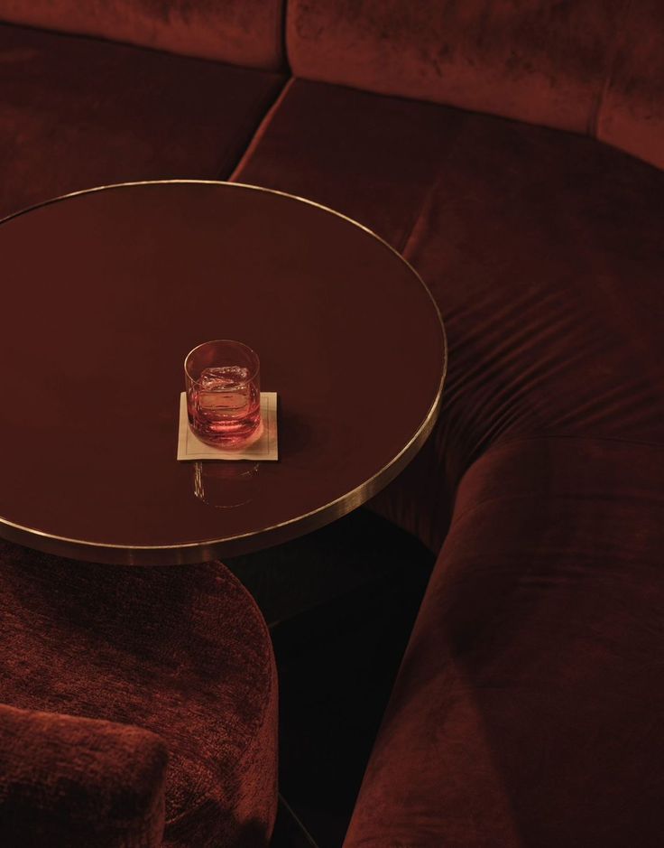 A moody curved velvet booth and glossy table in deep brown
