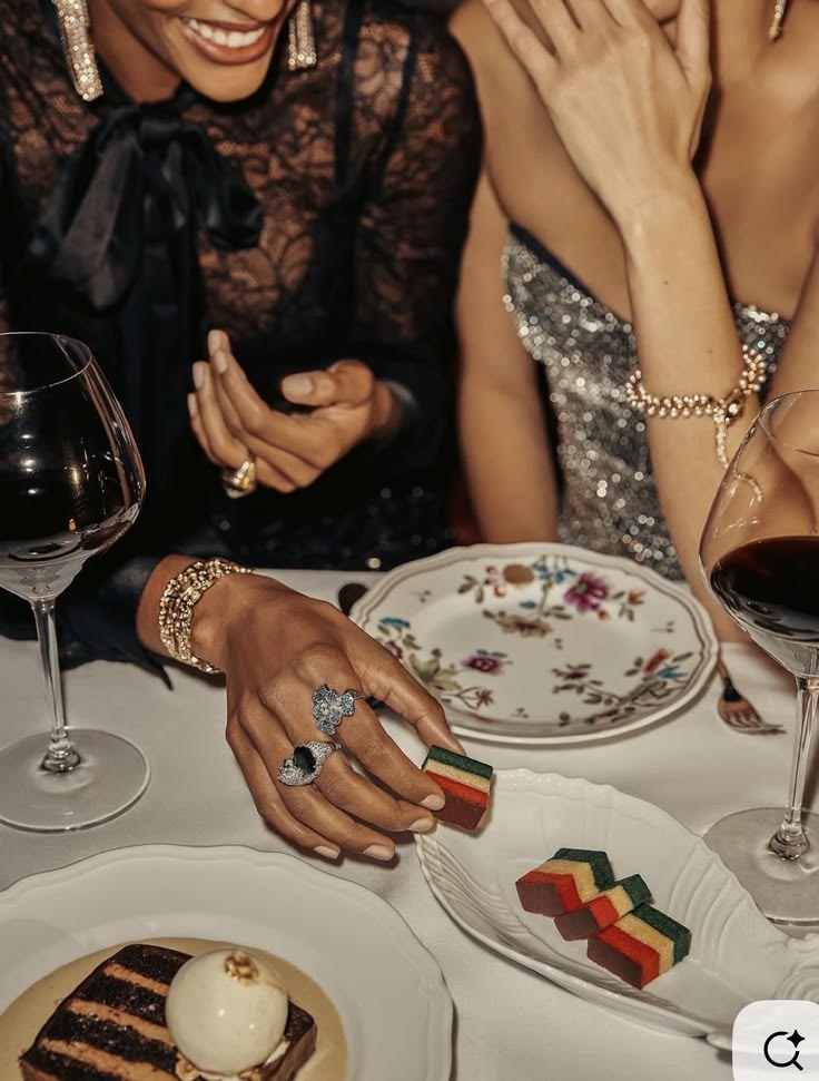 Two women laughing over wine and dessert at an intimate table