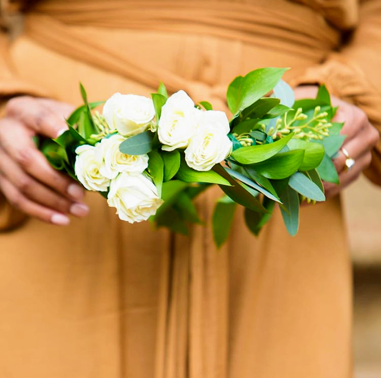 A fresh white rose crown held in two hands