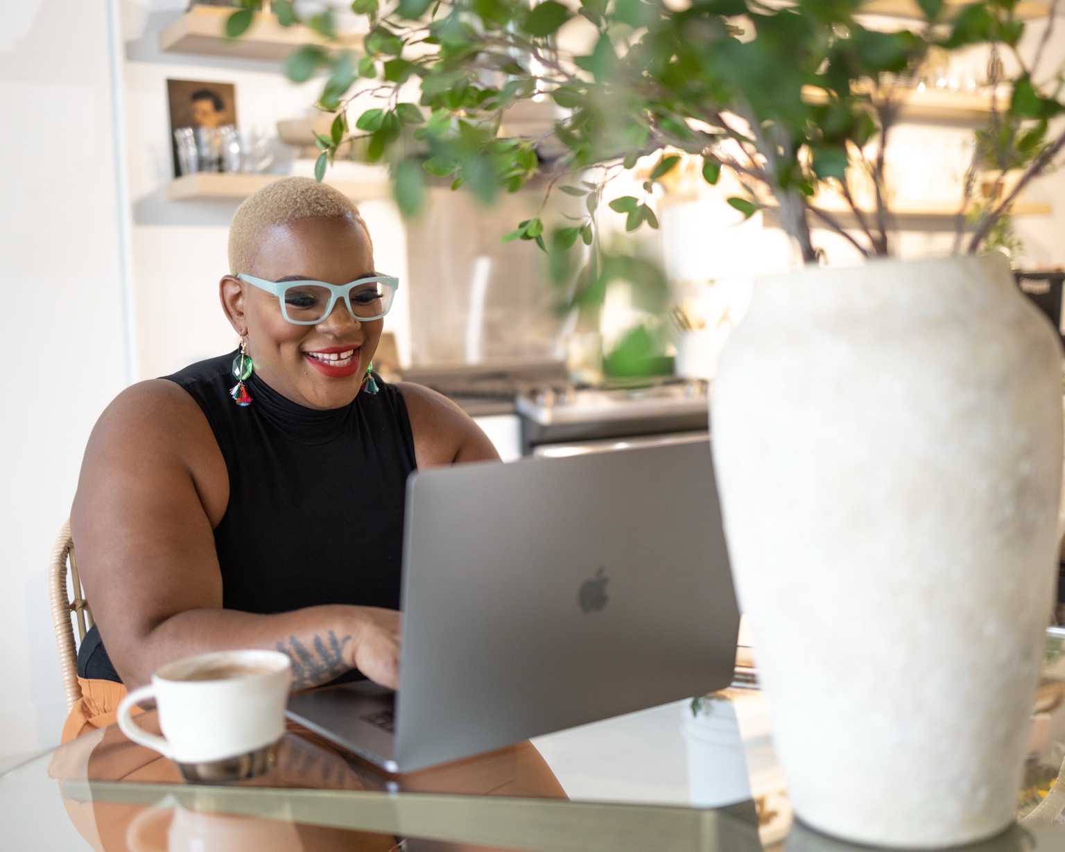 Ronisha Arlene smiling as she works at a laptop with coffee nearby