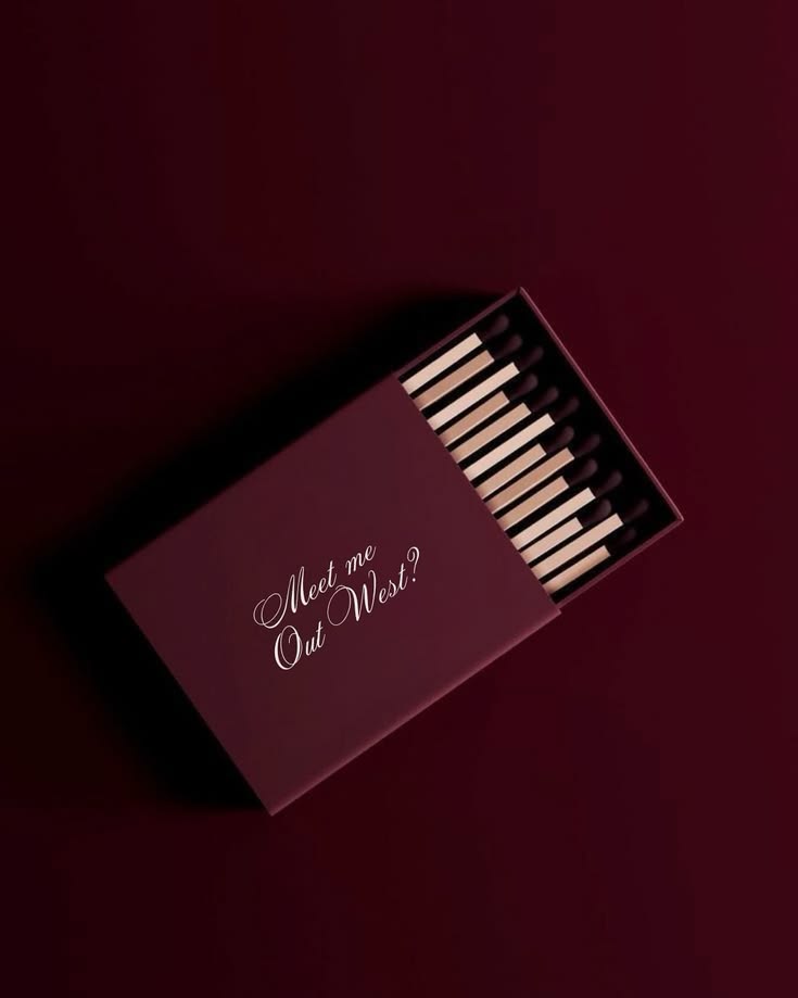 A burgundy matchbook on a deep aubergine surface