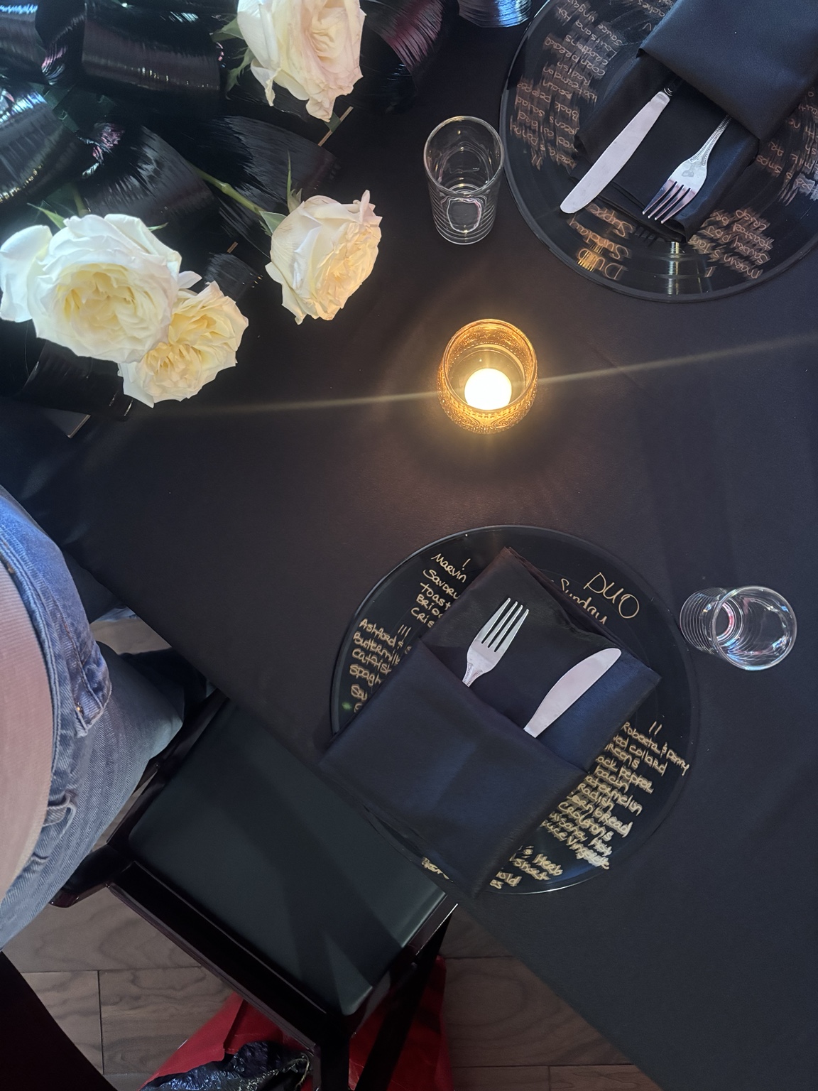 Black linens, white roses, candlelight, and vinyl record menus set for DUO Sunday Supper