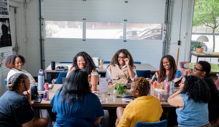 Black women gathered around a table in joyful conversation
